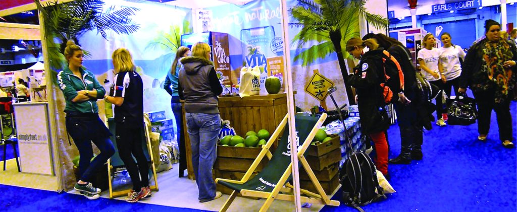 A group of people are gathered around a convention booth with a tropical theme.