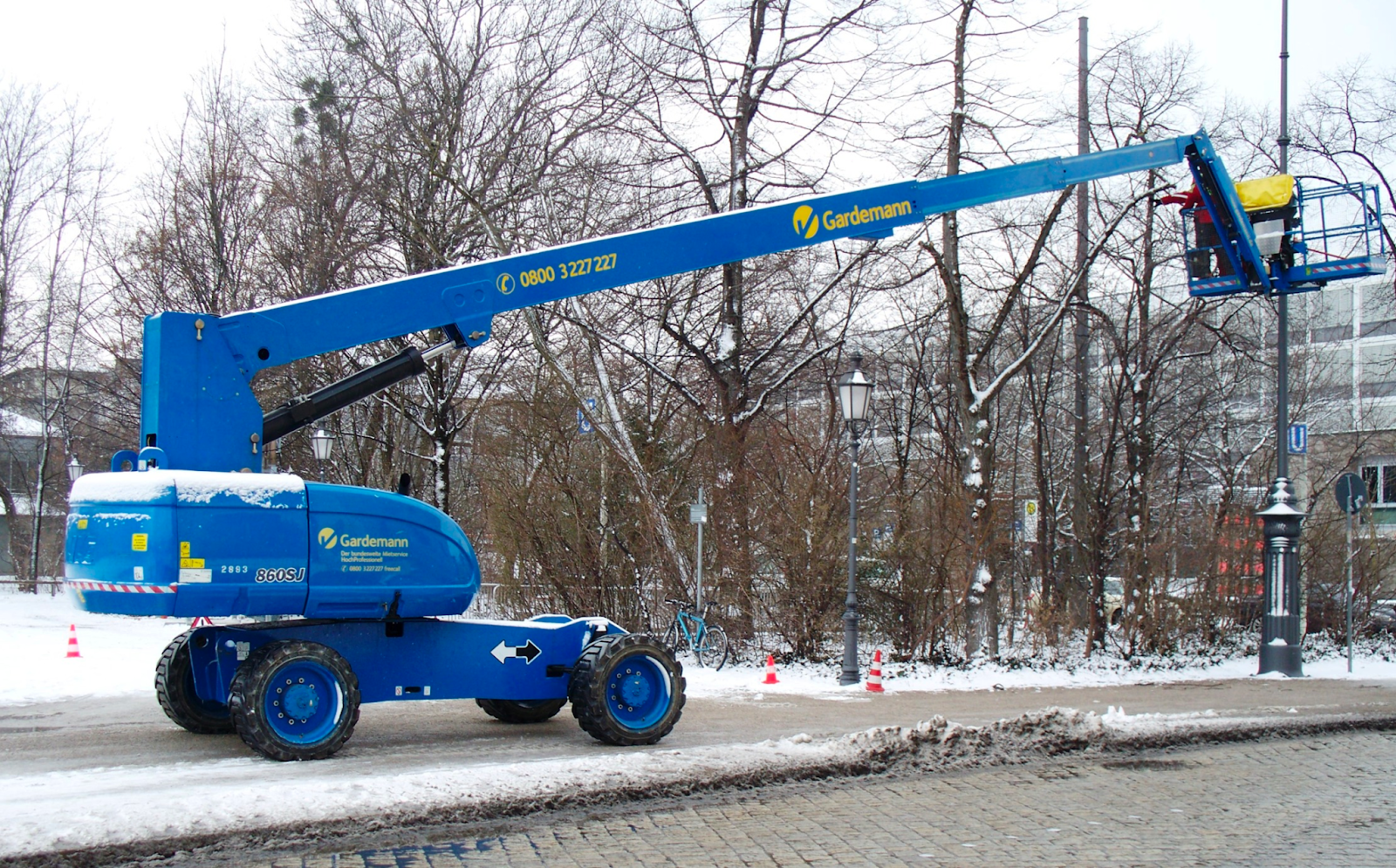 A large boom lift parked outside on a snowy sidewalk.