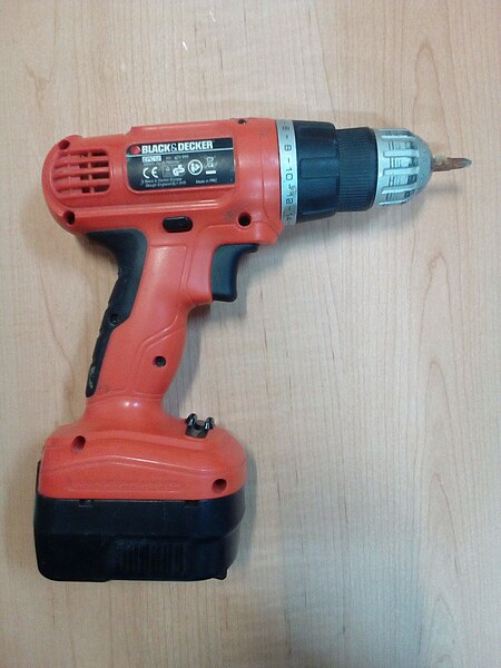 A hand-held, battery-powered drill. A rectangular battery pack is attached to the bottom of the handle. The handle has a trigger to start the drill. A screwdriver bit is installed.