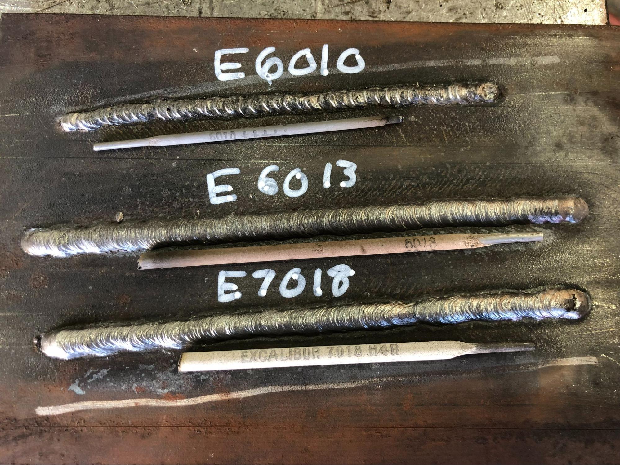 A piece of plate with three weld beads made with different electrodes. Each of the beads is labeled, E6010, E6013, and E7018.