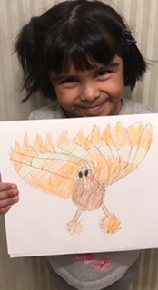 Kindergarten student holding her drawing of a turkey.