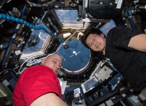 Astronauts Scott Tingle (left) and Norishige Kanai (right) watch the SpaceX Dragon cargo craft arrive from inside the seven-windowed Cupola moments before capturing it with the Canadarm2 robotic arm.