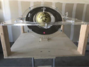 The provided image displays an orbital demonstrator utilized in a first astrodynamics class at the University of Colorado, Colorado Springs. This custom-designed and built demonstrator serves as a valuable educational tool for visualizing three-dimensional orbits. It likely incorporates various elements to represent key astrodynamics concepts, offering students a hands-on experience in understanding the complexities of orbital mechanics. The use of such demonstrators enhances the learning experience by providing a tangible and interactive way to explore celestial motion principles.