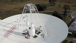 The provided image depicts crews conducting critical upgrades and repairs to the 70-meter-wide (230-foot-wide) radio antenna Deep Space Station 43 in Canberra, Australia. This antenna is part of NASA's Space Network (SN), a crucial component for tracking and communicating with satellites in orbit. The SN's architecture involves two segments: the space segment, featuring a constellation of Tracking and Data Relay Satellites (TDRS) in geosynchronous orbit, and the ground segment, which comprises a series of ground-based antennas. In this clip, one of the antenna’s white feed cones (which house portions of the antenna receivers) is being moved by a crane. The 70-meter-wide antenna in Canberra is a vital element of the network, enabling reliable and secure relay communications and tracking services for various space missions.