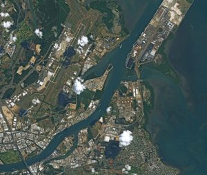 Aerial view of Brisbane, Australia captured by the SPOT-6 satellite. The image shows the urban landscape, river, and surrounding areas with a mix of buildings, parks, and infrastructure.