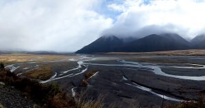 Multiple small rivers converge leading to a mountain surrounded by clouds