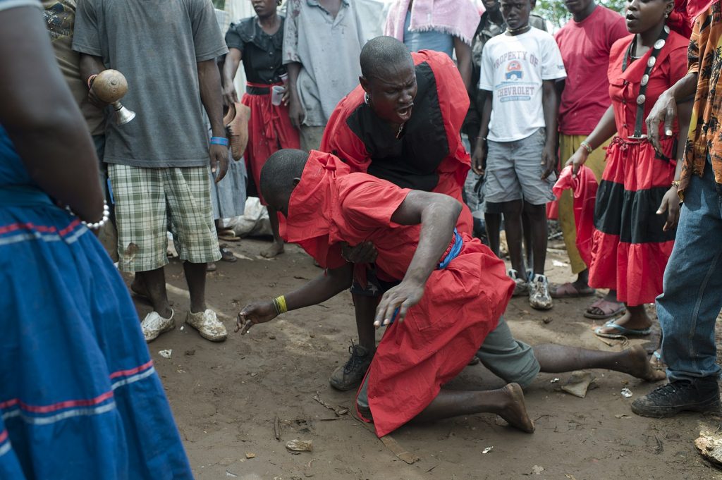 Man holding falling woman during a vodou ceremony