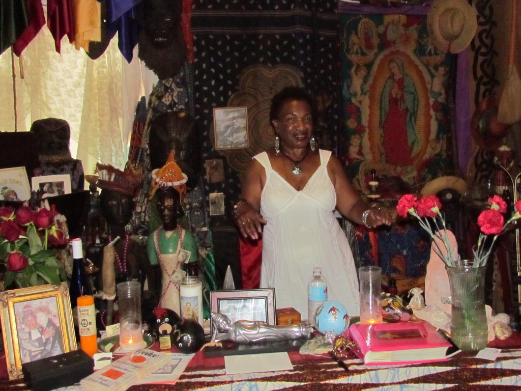 Voodoo Priestess Miriam standing behind an altar