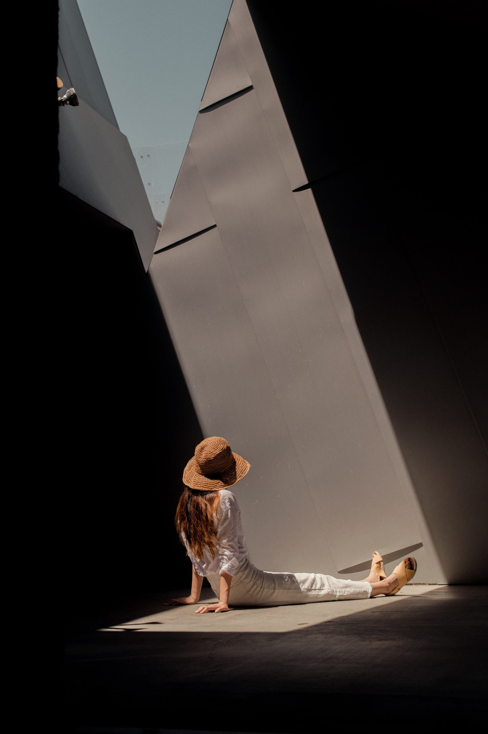 Woman sitting on the ground near a vertical contemporary statue