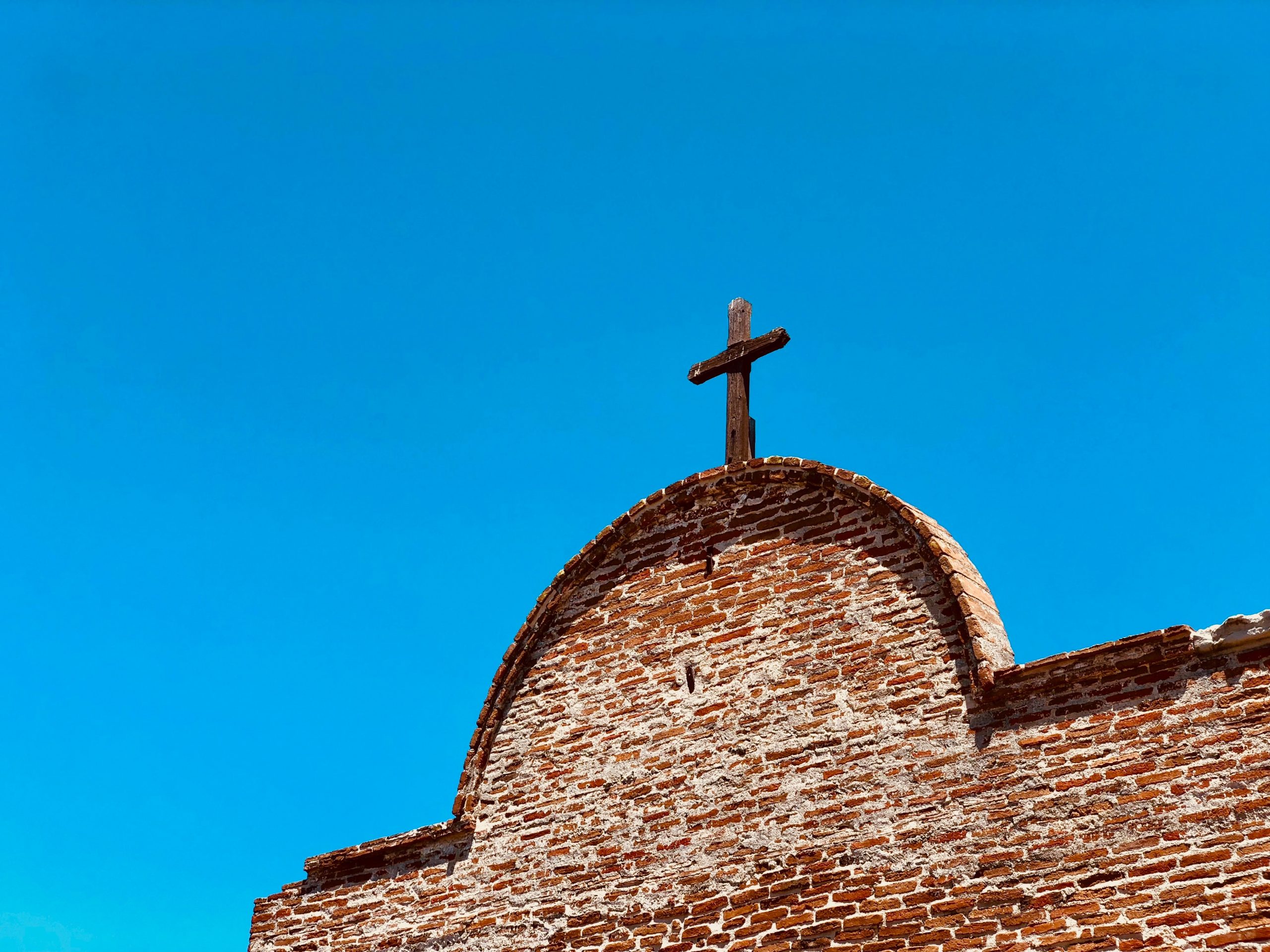 Image of cross on top of a mission style building