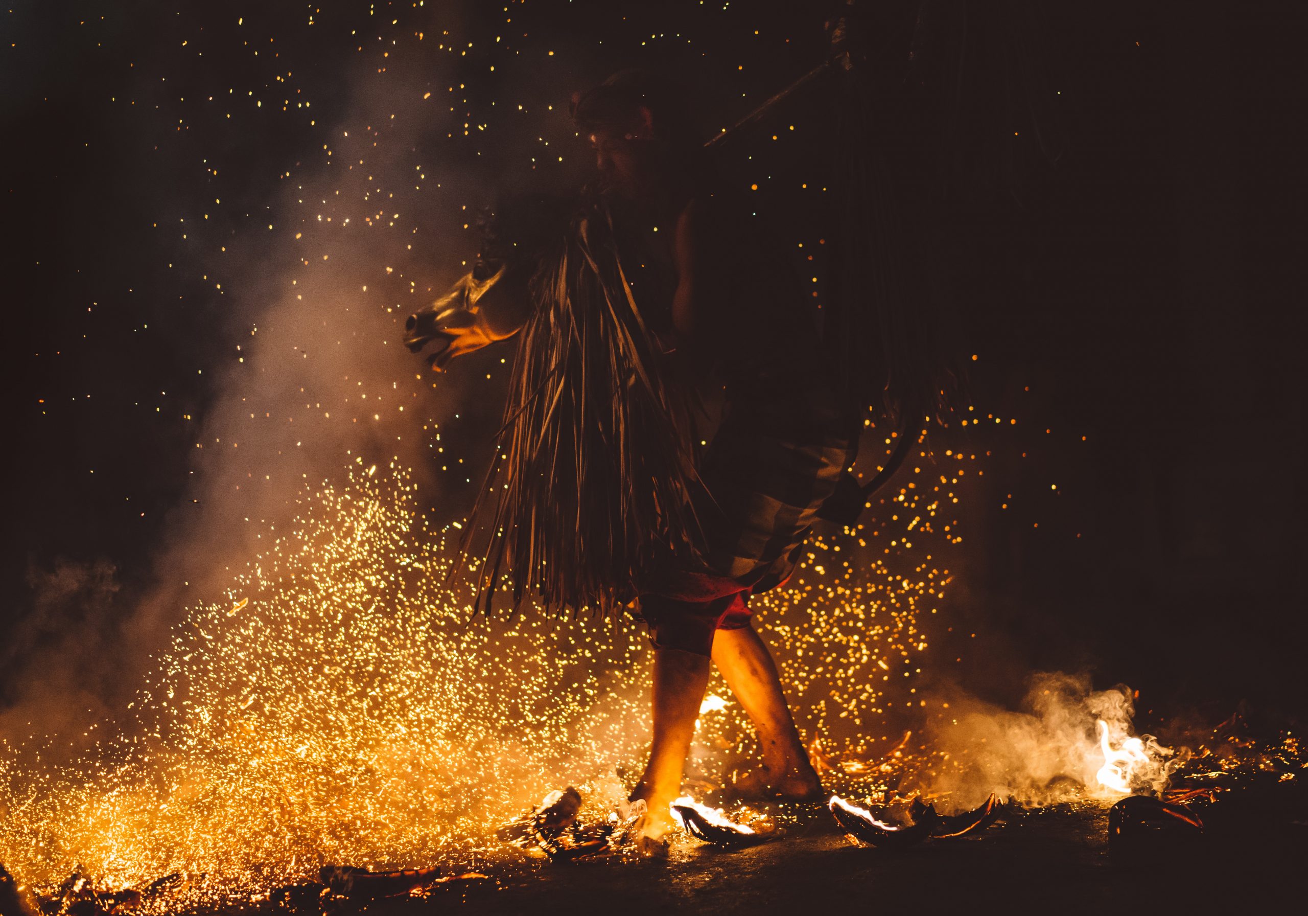 Barefoot person dressed in Balinese traditional clothing dancing in fire