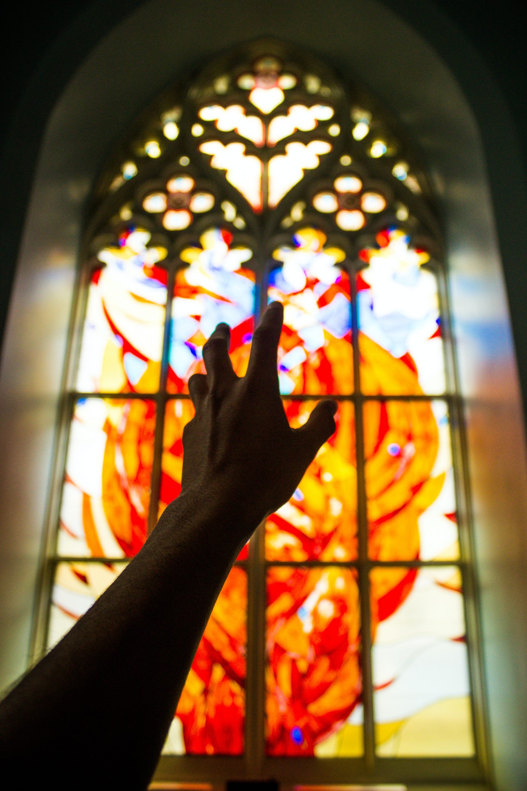 Hand in front of a church's stained glass window
